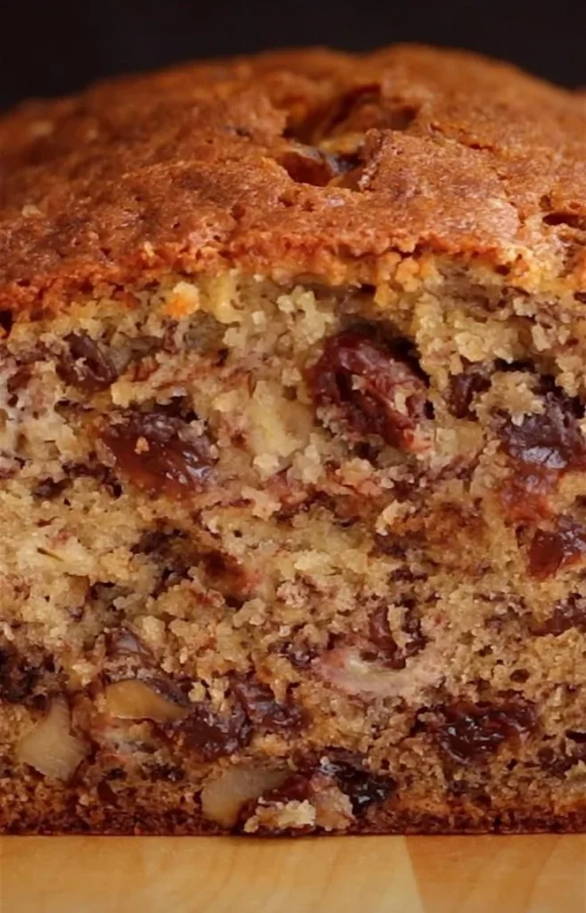 Slice of incredibly moist banana bread on a wooden cutting board.
