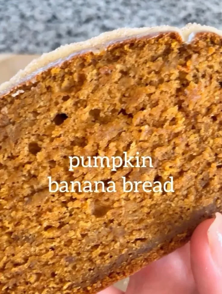 Freshly baked pumpkin banana bread with spices and walnuts on a wooden table.